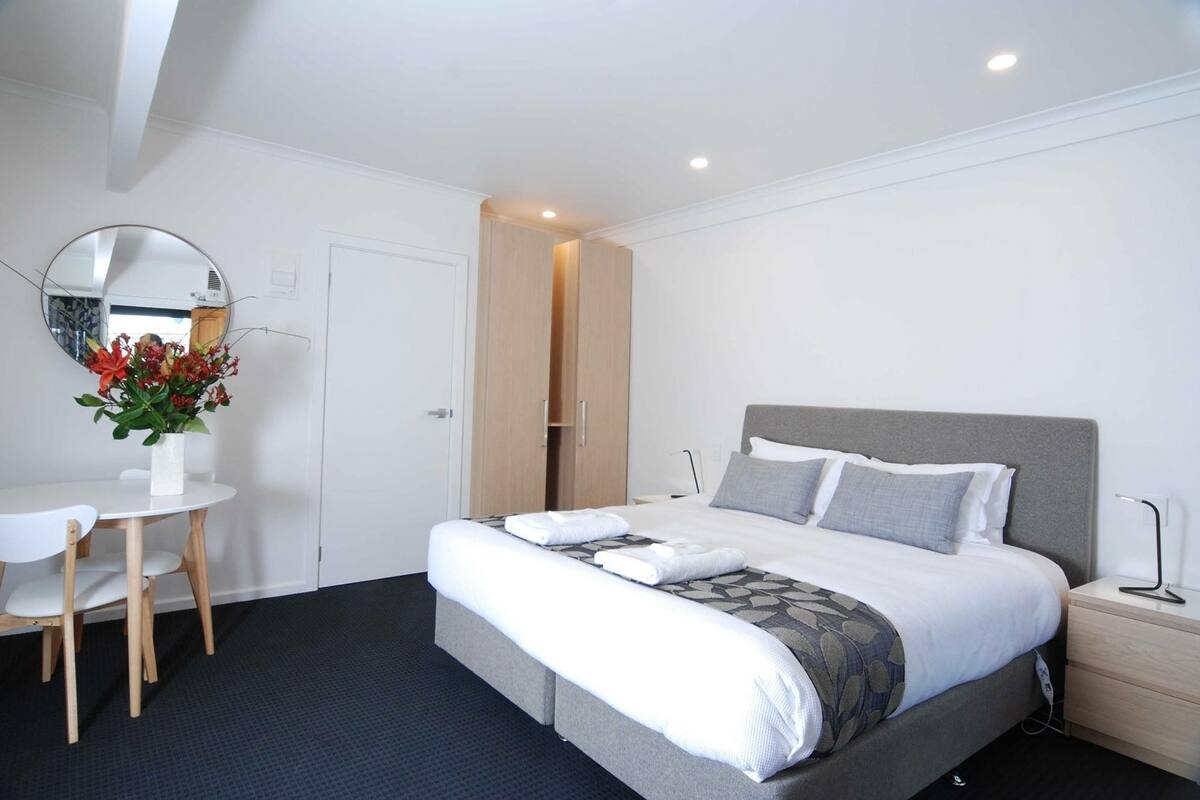 Una habitación de hotel moderna con una cama, una mesita de noche y un escritorio con una silla.