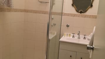 A bathroom with a glass-enclosed shower, a sink with a mirror above it, and a toilet.