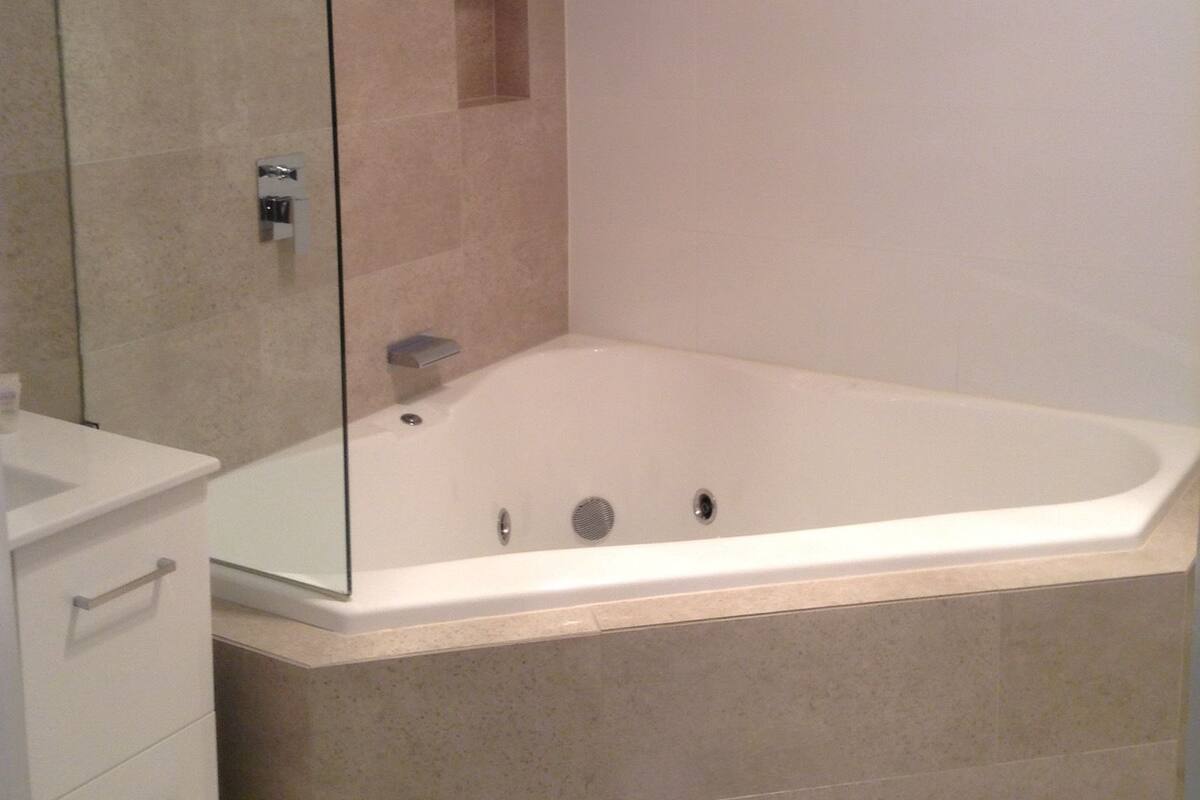 Un baño moderno con ducha envuelta en vidrio, una bañera independiente y un tocador minimalista.
