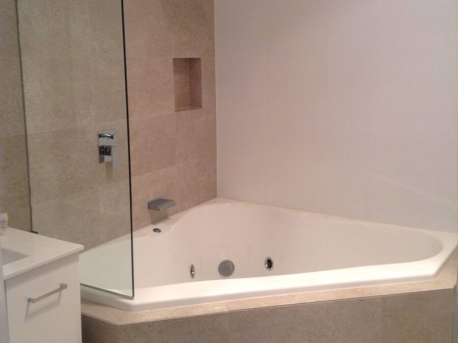 Et moderne badeværelse med et glasafskærmet brusebad, et fristående badekar og et minimalistisk toiletbord.