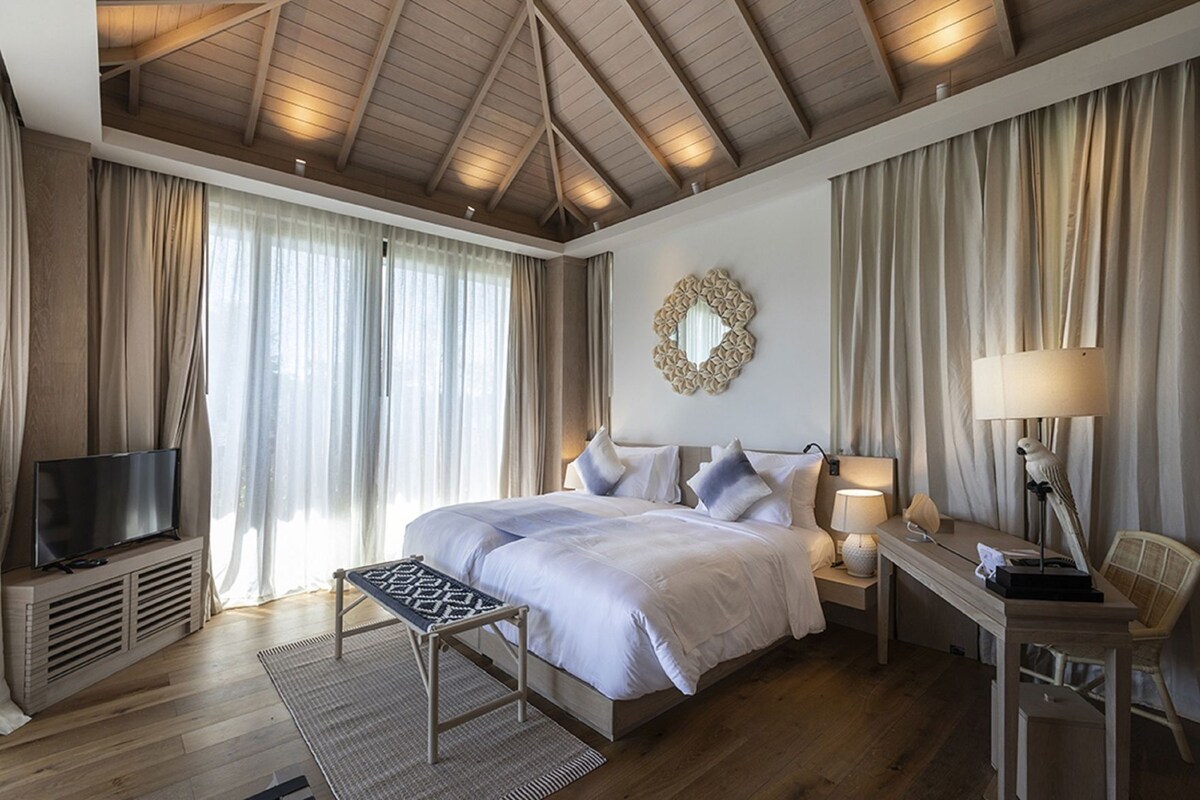 A bedroom with a bed, bedside tables, a TV, and a desk with a lamp.