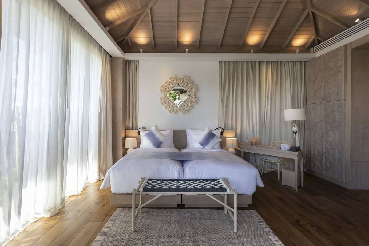 A bedroom with a bed, bedside tables, a desk, and a decorative wall piece.