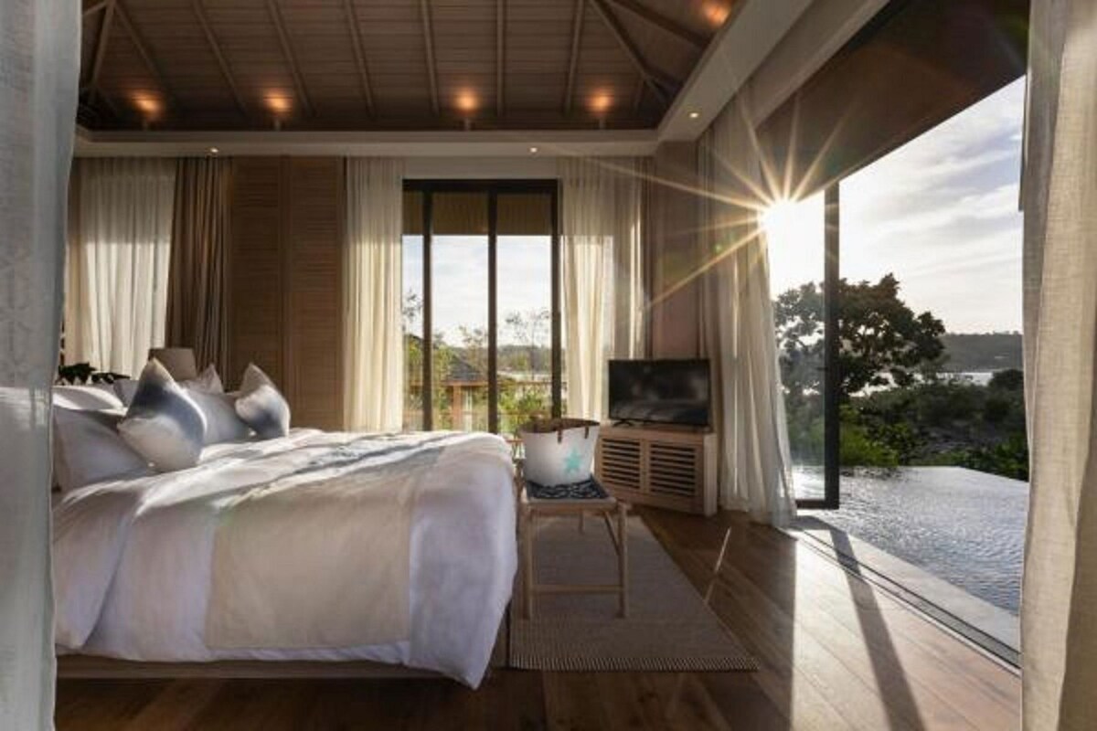 A bedroom with a large bed, a TV, and a view of the outdoors.