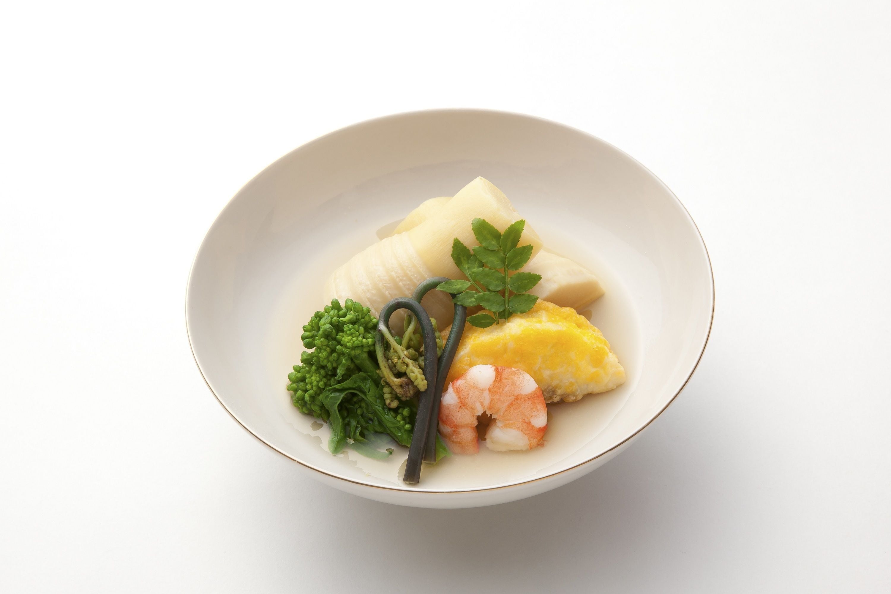 A bowl of food with a white plate, containing a piece of fish, a shrimp, a slice of egg, and some greens.