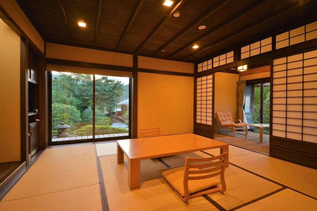 A tatami mat room with a sliding door, a wooden table, and a chair.