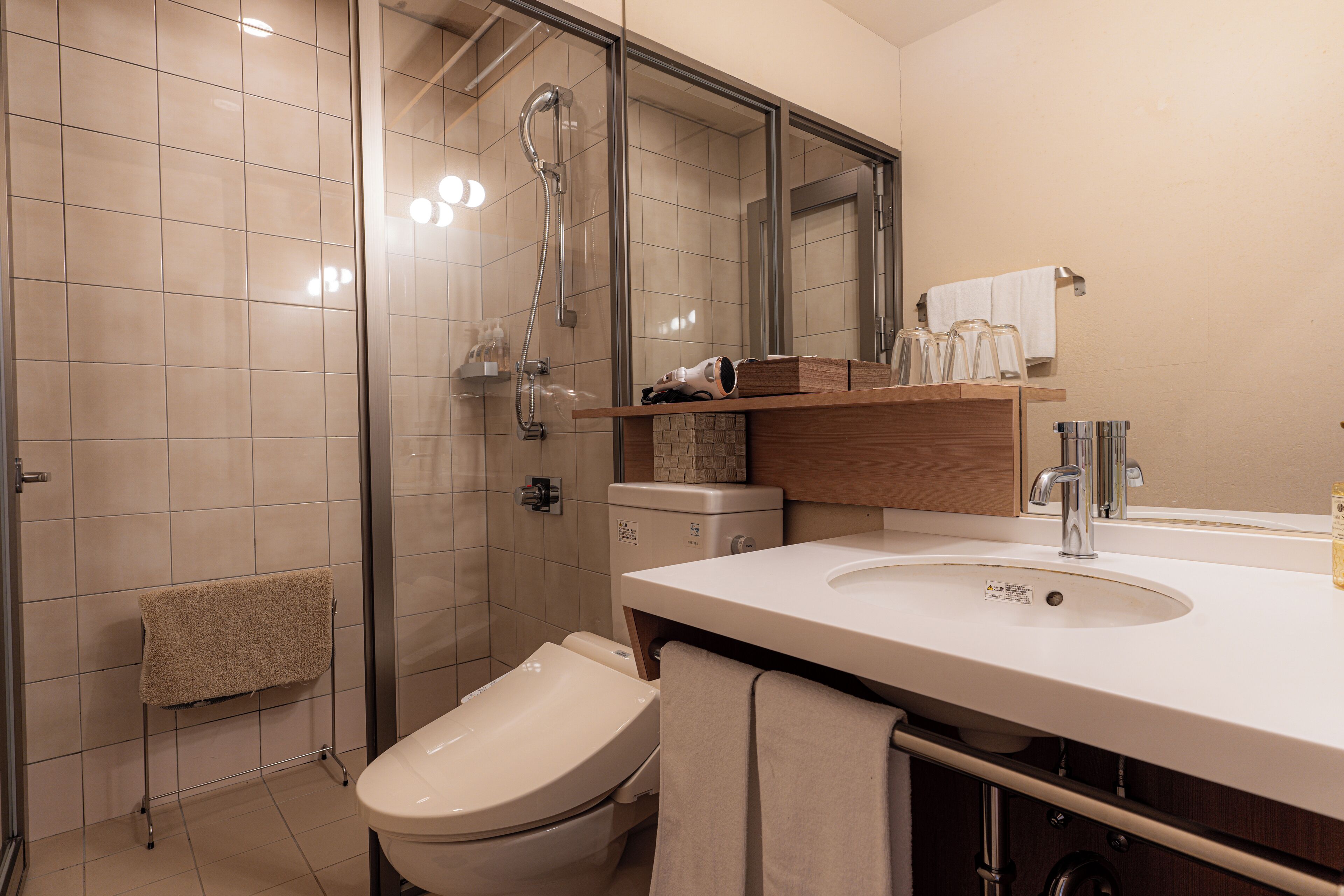 A modern bathroom with a glass-enclosed shower, a toilet, and a sink with a mirror above it.