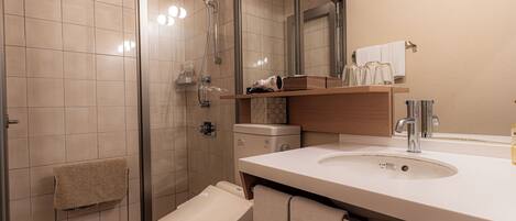 A modern bathroom with a glass-enclosed shower, a toilet, and a sink with a mirror above it.