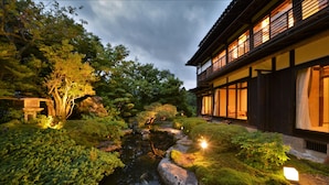 Un jardín japonés tradicional con un estanque de carpas, rocas y abundante vegetación.