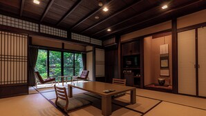 Una habitación japonesa tradicional con suelo de tatami, una mesa baja y asientos.