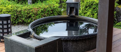 Un jacuzzi de piedra con cubierta de madera y un farol.