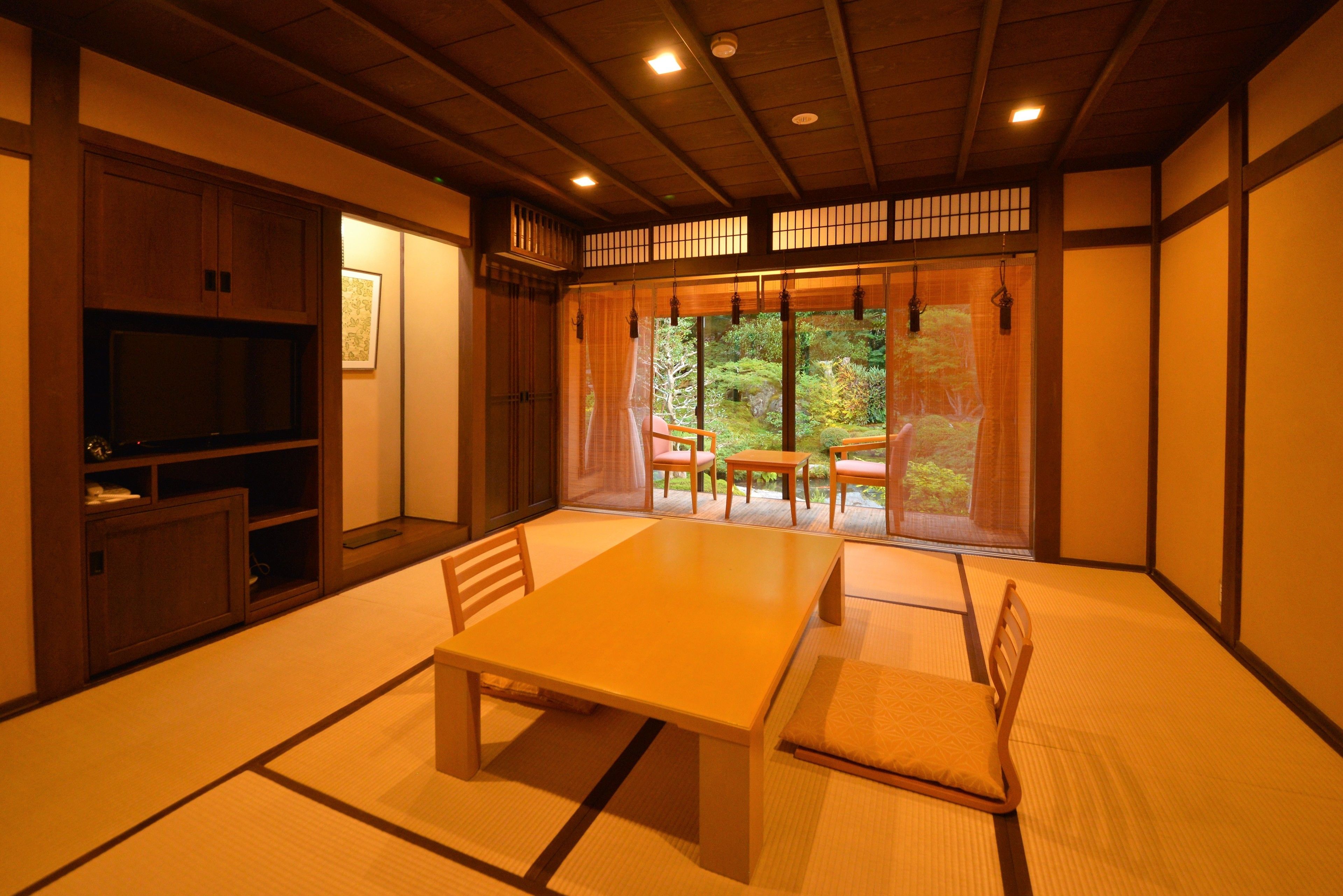 A traditional Japanese room with tatami flooring, a low table, and sliding doors leading to a garden.