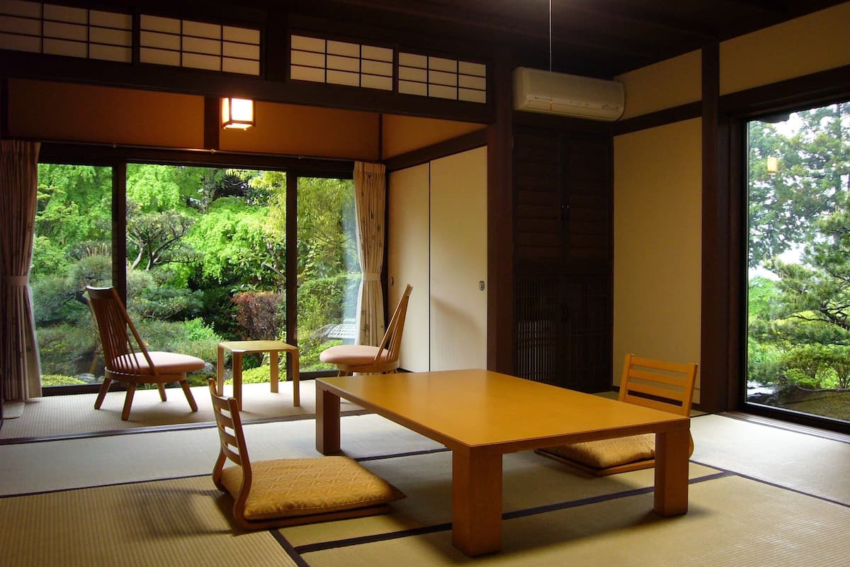 A traditional Japanese room with tatami flooring, a low table, and chairs.