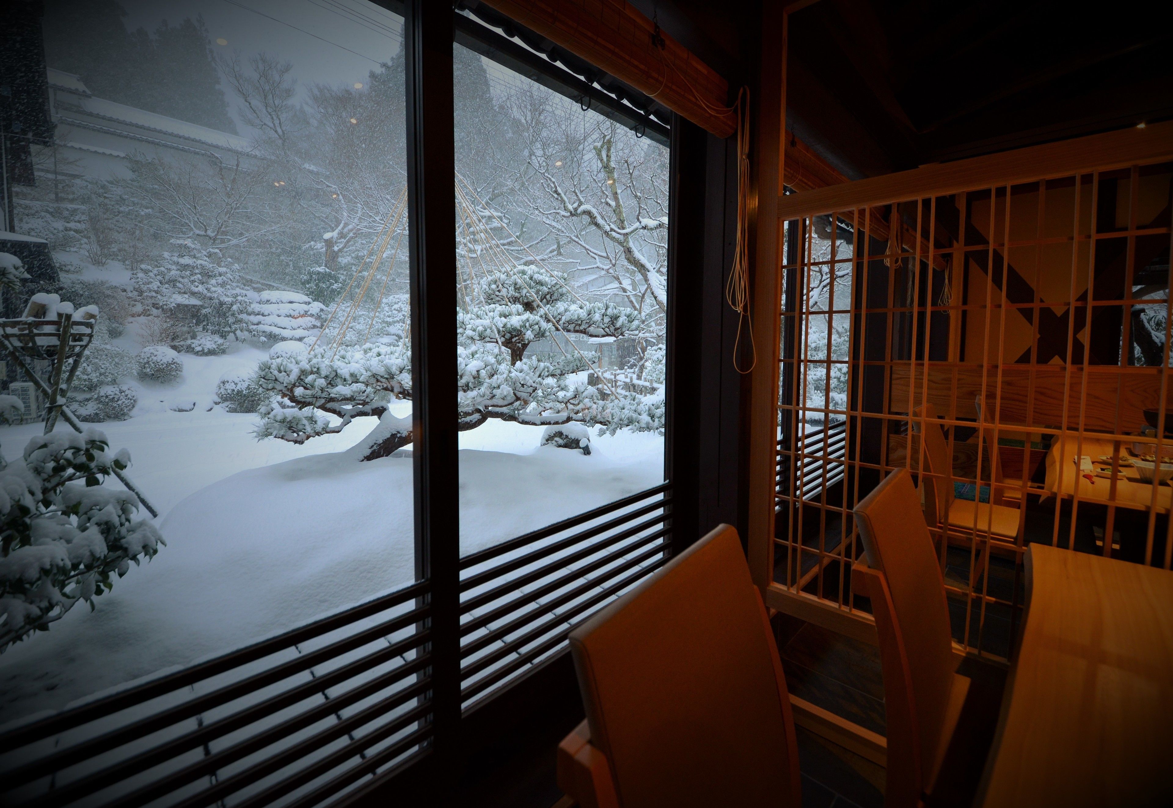 Una habitación con un gran ventanal que da a un jardín cubierto de nieve.
