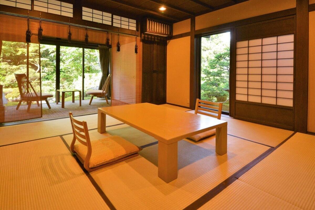 A traditional Japanese room with tatami flooring, a low table, and chairs.