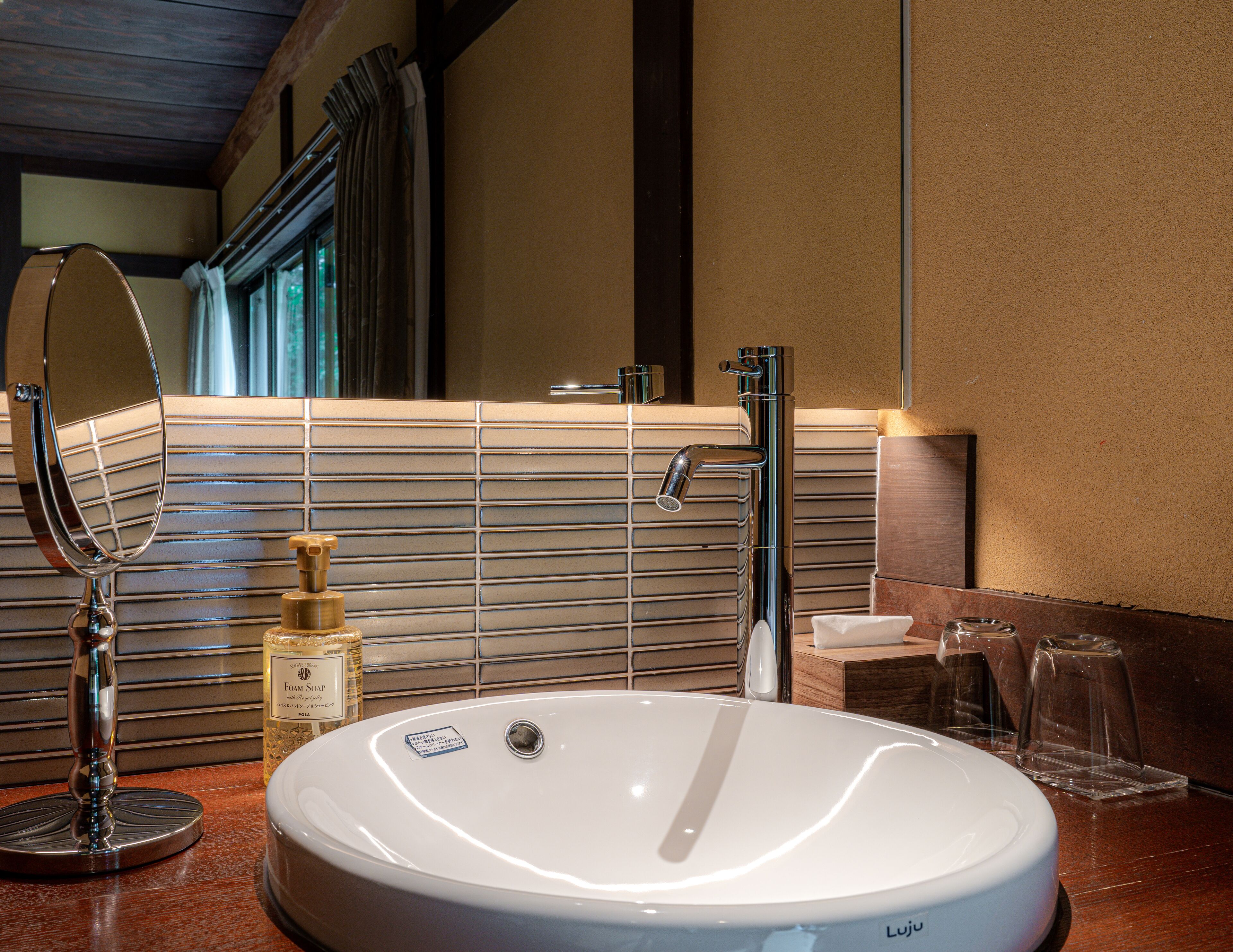 A bathroom with a white sink, a mirror, a soap dispenser, and a towel rack.