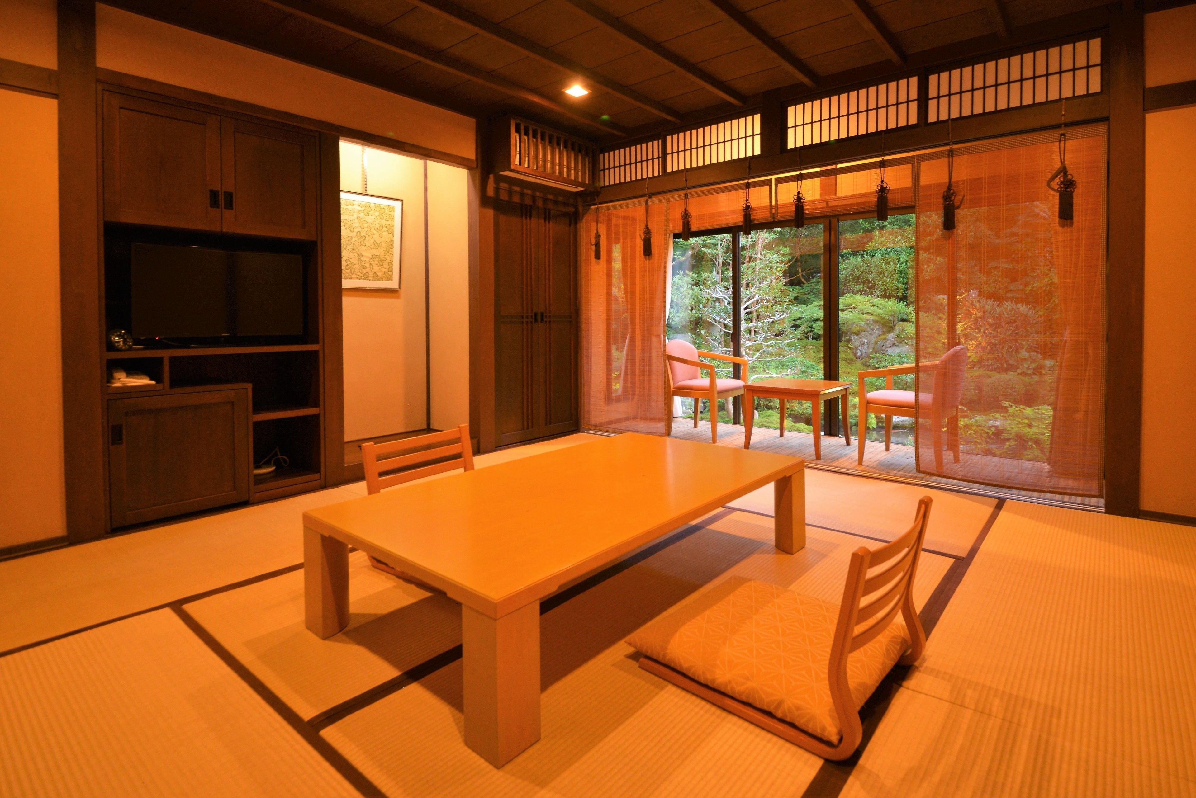 A traditional Japanese room with tatami flooring, a low table, and sliding doors leading to a garden.
