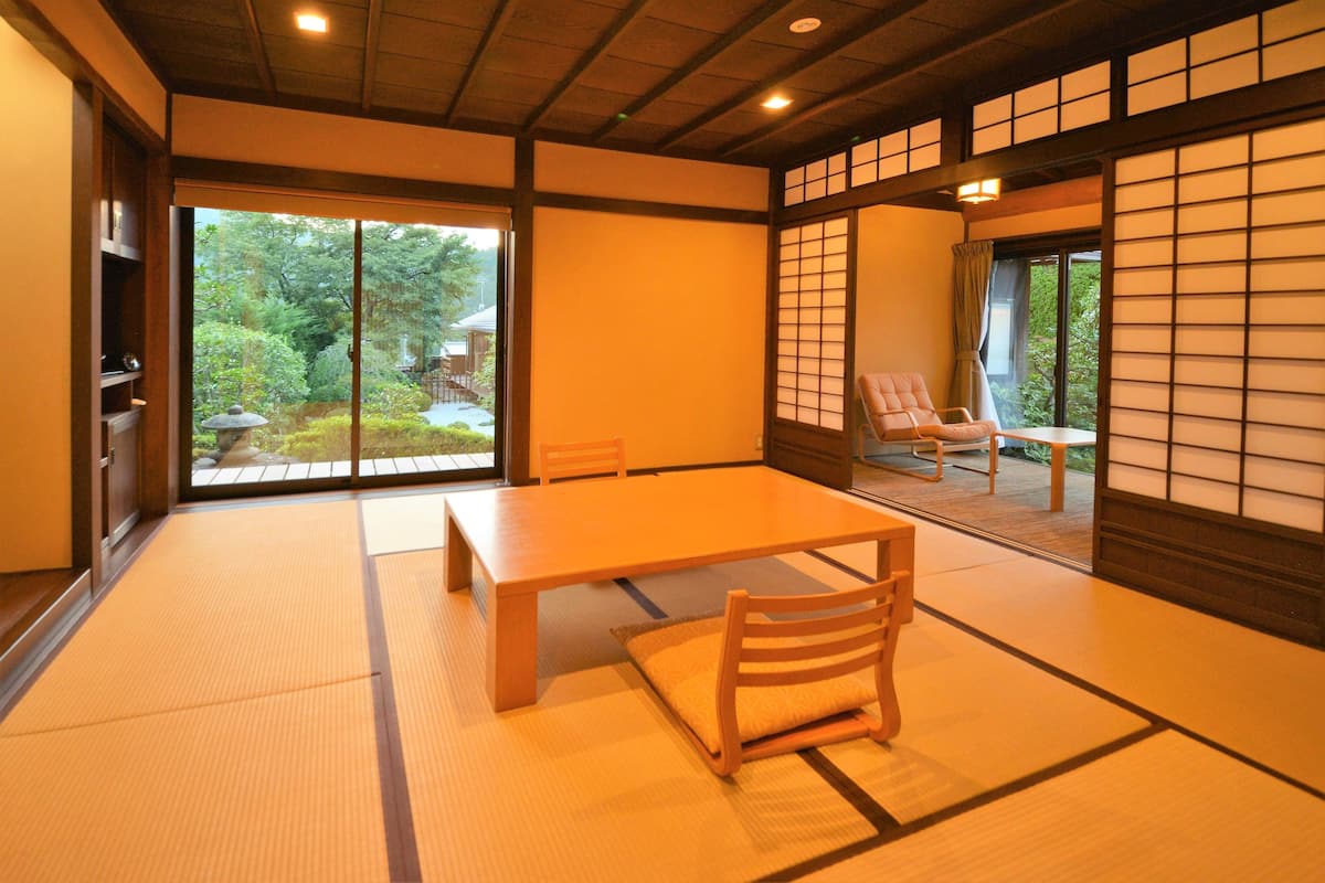 A traditional Japanese room with tatami flooring, a low table, and a chair.