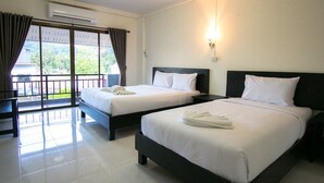 A hotel room with two beds, a balcony, and a view of greenery. - Memory Place (Krabi)