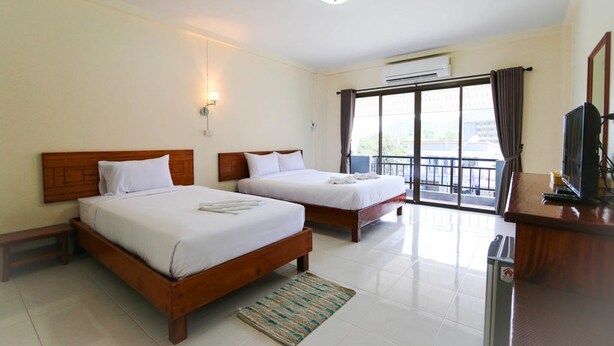 A hotel room with two wooden beds, a small desk with a television, and a balcony with a view. - Memory Place (Krabi)