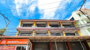 A multi-story building with a closed shop on the ground floor, a balcony on the second floor, and visible electrical wires. - Memory Place (Krabi)