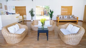 Quarto com móveis de vime, um balcão de recepção e vista para o exterior.