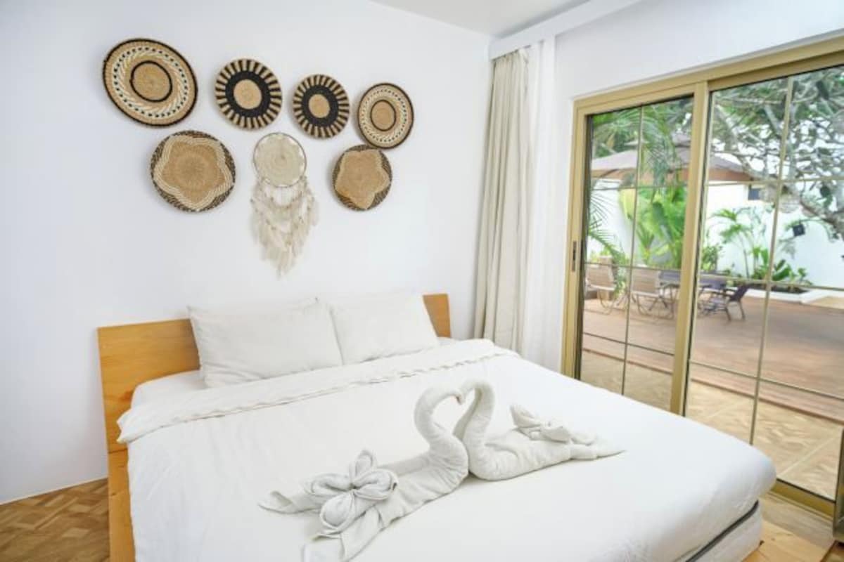 A hotel room with a bed, a large window with a view of palm trees, and wall decor.