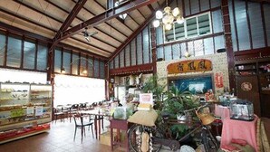 A spacious restaurant with high ceilings, wooden beams, and large windows. Tables and chairs are arranged for dining, and a bicycle is parked inside. - Phoenix Landscaping B&B (Yuanshan)