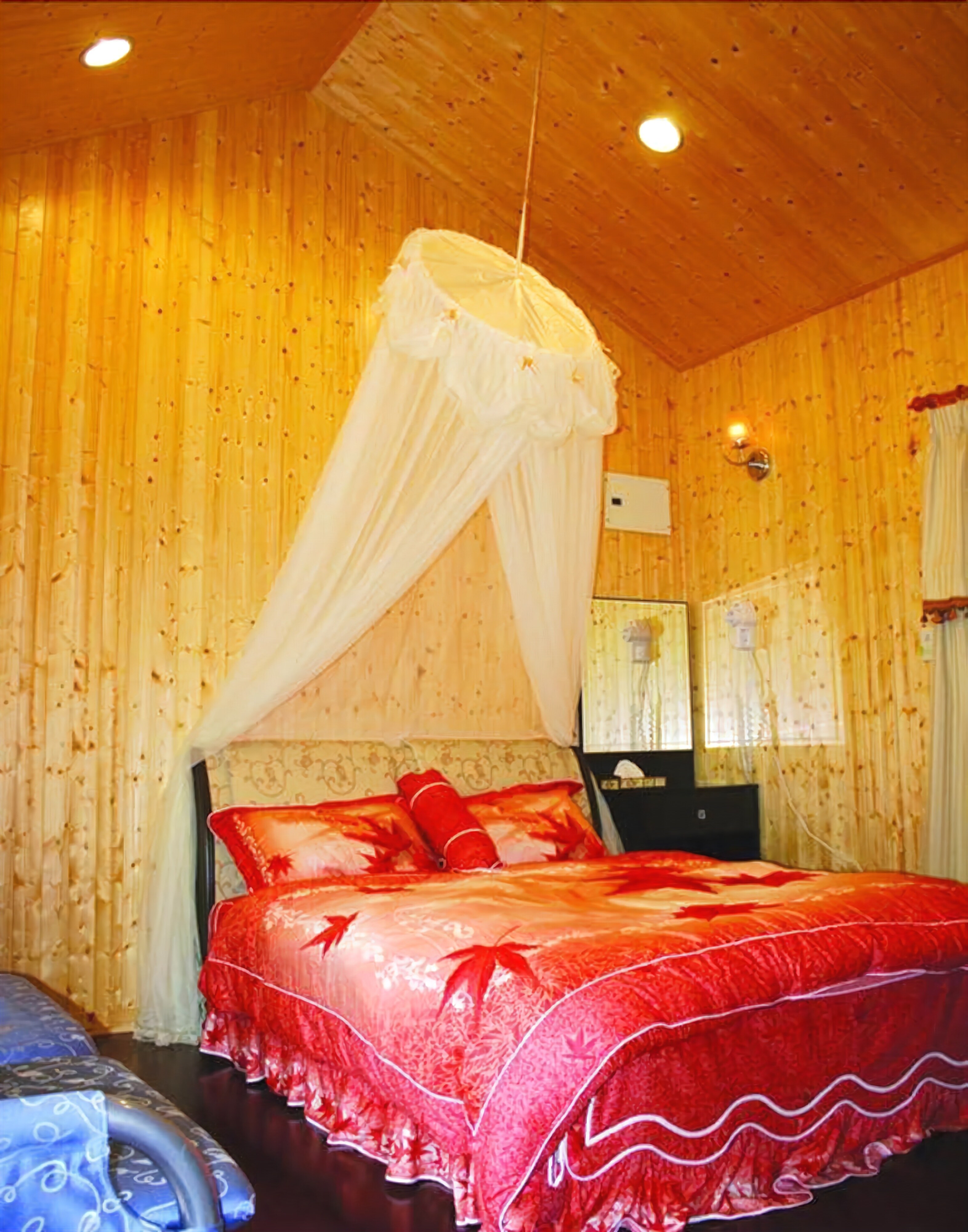 A bedroom with a canopy bed, wooden walls, a bedside table, and a mirror.