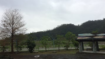 A park with a pavilion, trees, a pond, and a hilly background.