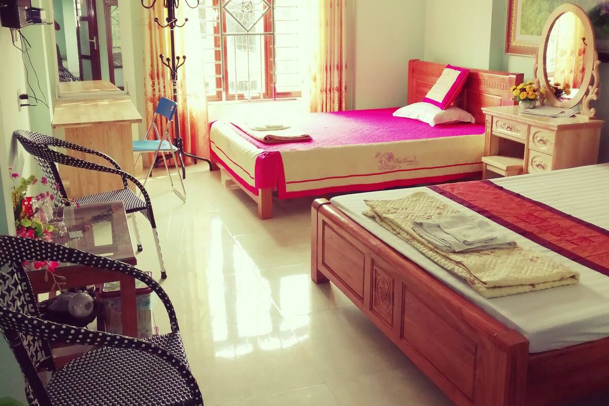 Une chambre avec deux lits, une chaise, un bureau, un miroir et une fenêtre avec des rideaux.