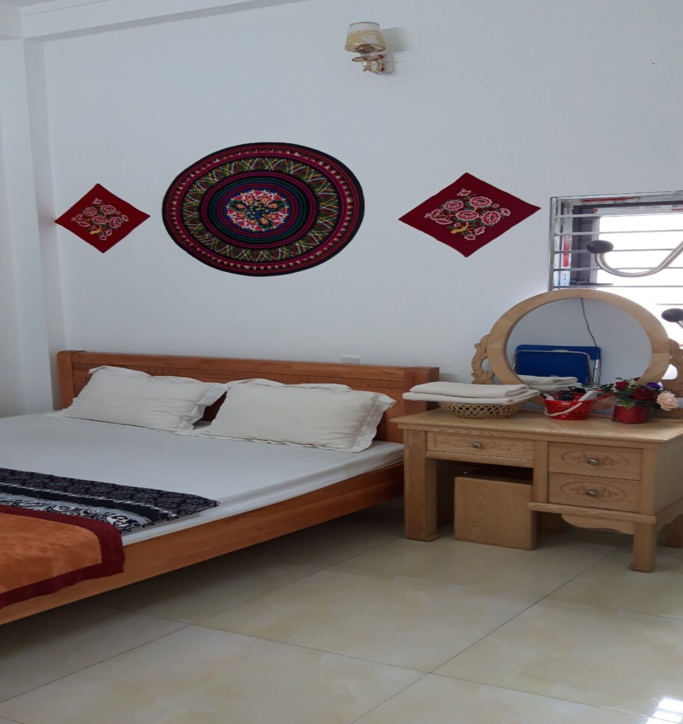 Un dormitorio con una cama de madera, una mesita de noche de madera con espejo y adornos en la pared.