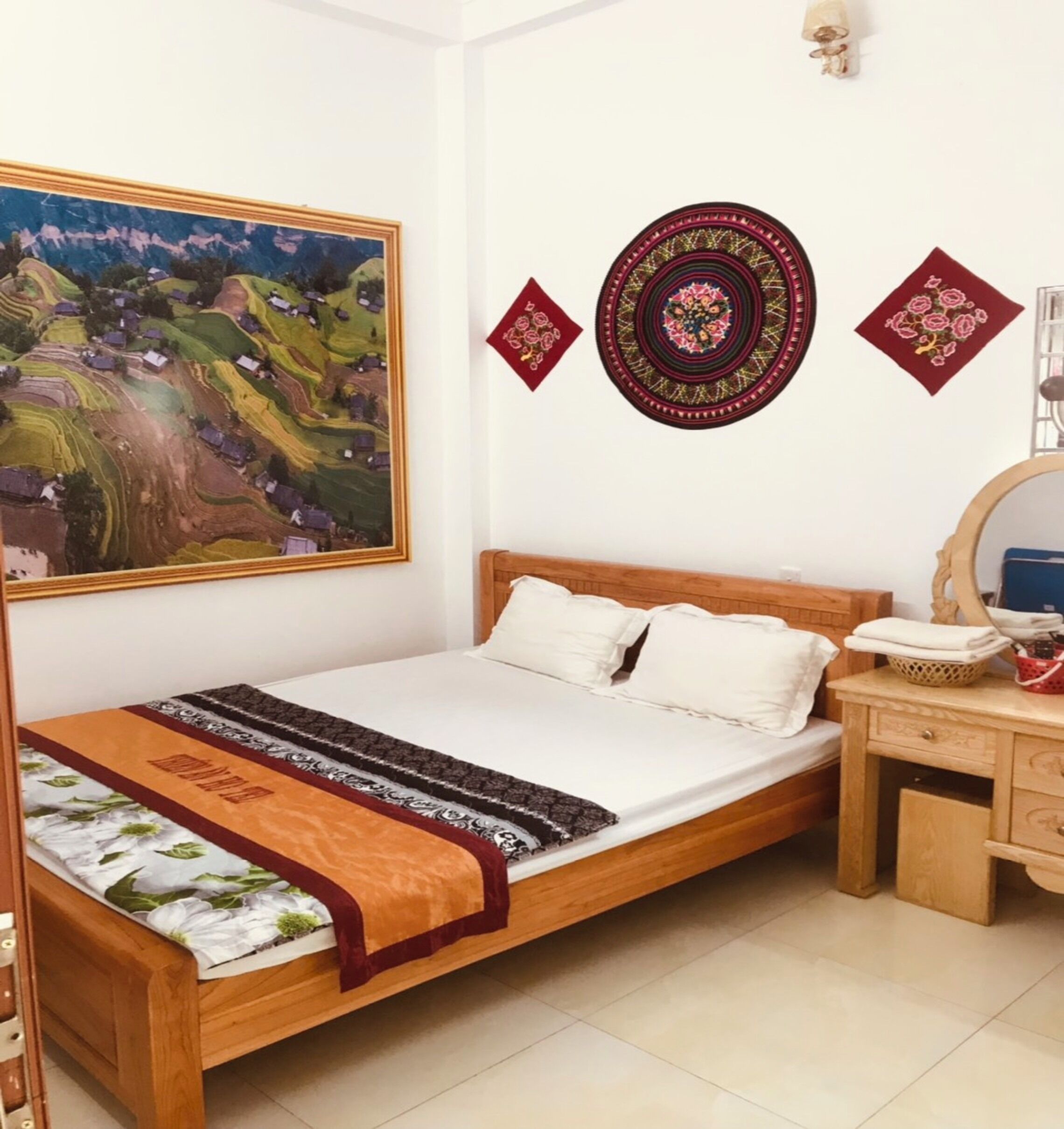 Une chambre à coucher comprenant un lit, une table de chevet en bois, un miroir et un mur orné d’un tableau et de décorations murales.