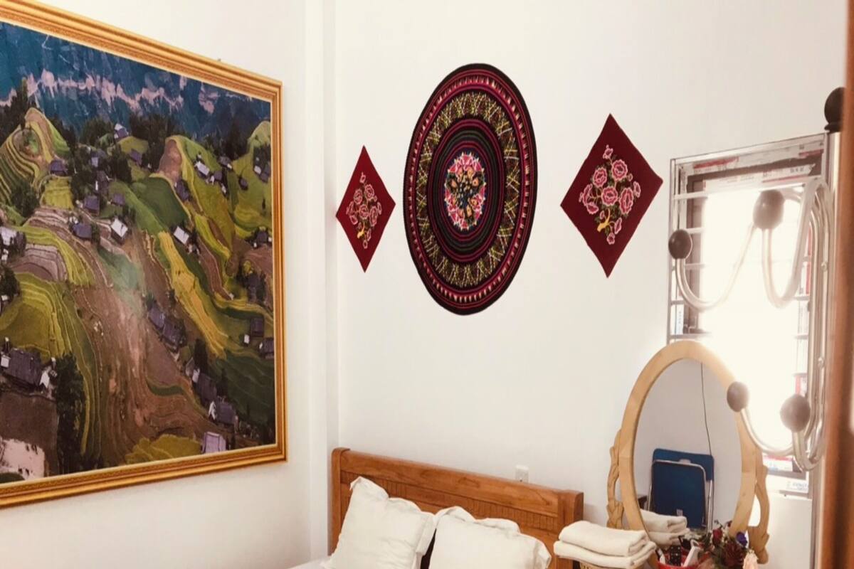 Une chambre à coucher avec un lit, une commode en bois, un miroir et un tableau accroché au mur.