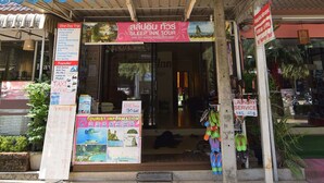 A building with a sign for 'Sleep Inn' and a 'Tourist Information' board. - Sleep Inn Hotel (Krabi)