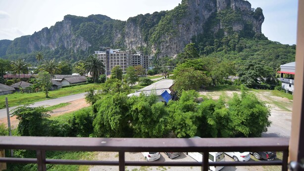 A residential area with a prominent mountain in the background, a road, and several parked cars. - Sleep Inn Hotel (Krabi)