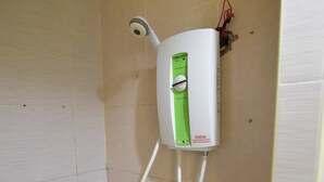 A bathroom with a wall-mounted water heater, a small shelf, and a showerhead. - Sleep Inn Hotel (Krabi)