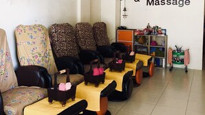 A room with multiple massage chairs, a wall sign reading "Sleep Inn & Massage," and a fan on the ceiling. - Sleep Inn Hotel (Krabi)
