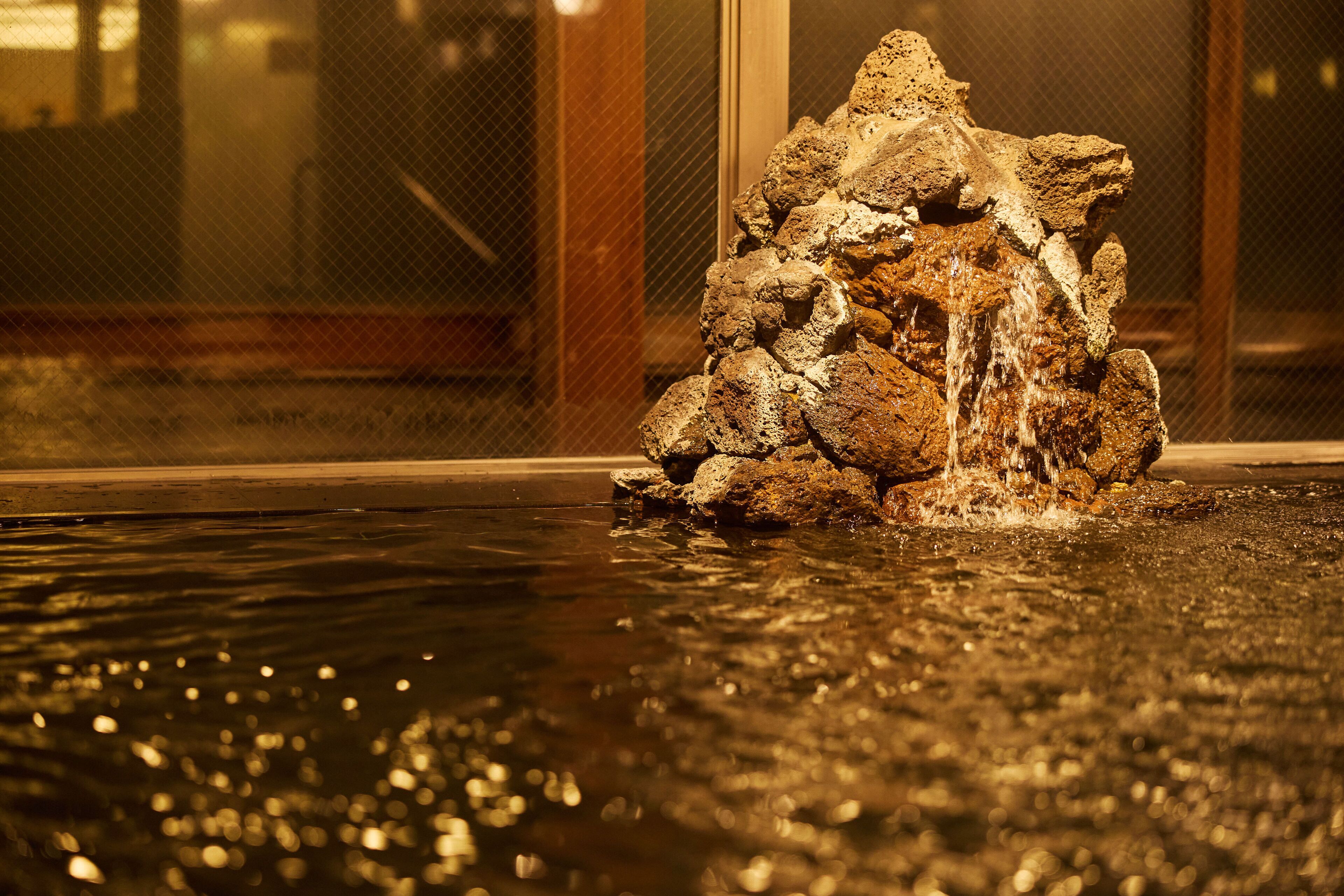 A water feature with a rocky structure in a pool area.