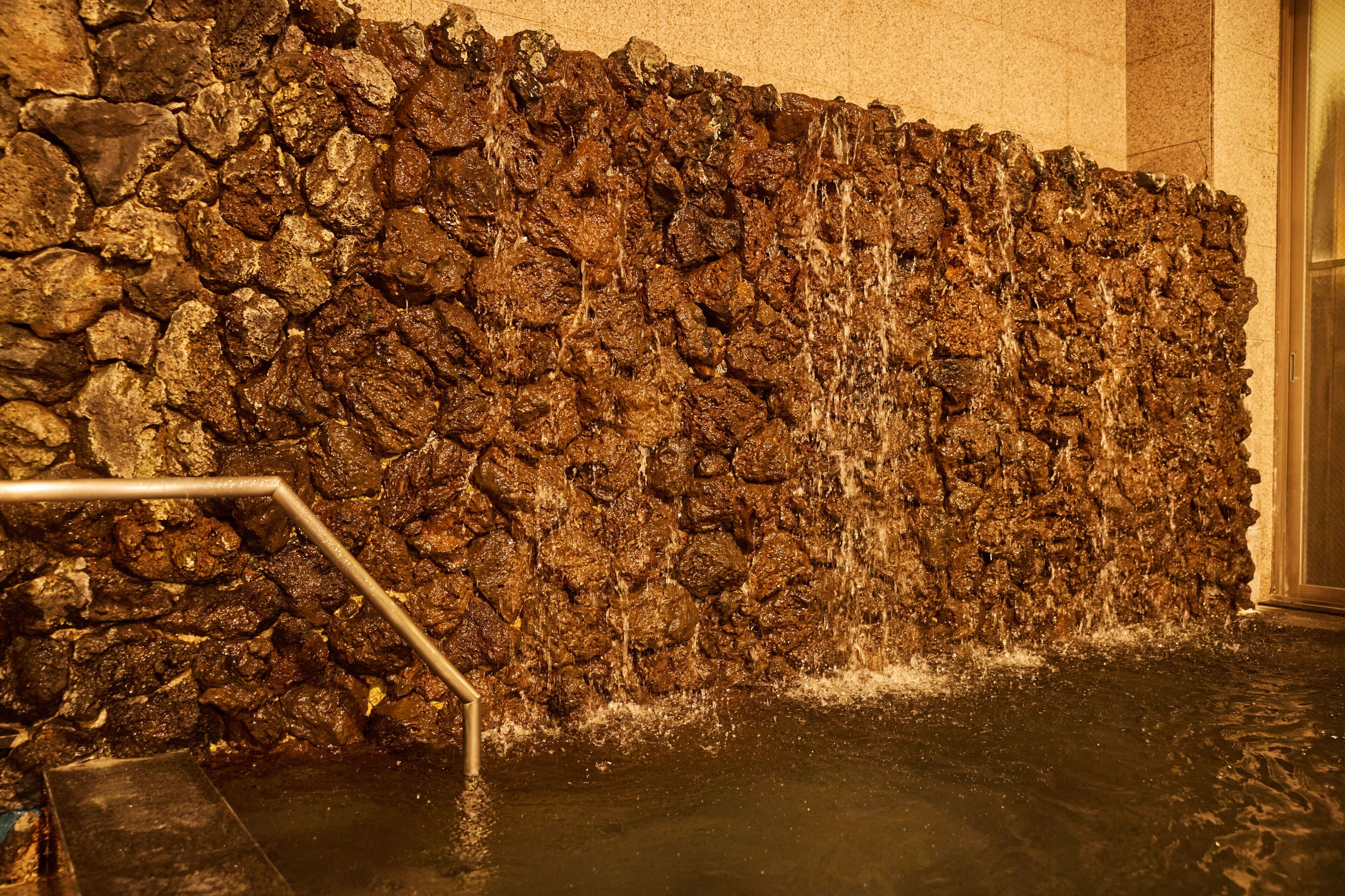 Una pared de piedra con agua cayendo en cascada.