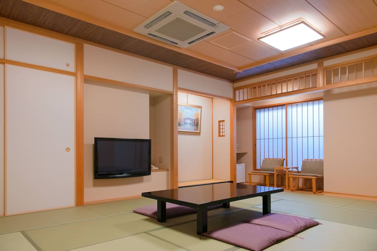 Una habitación tradicional japonesa con suelo de tatami, una mesa baja y un televisor.