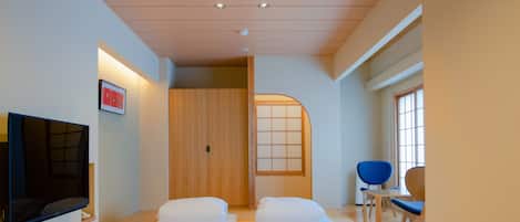 A room with two beds, a TV, a wooden wardrobe, and a window with a view.