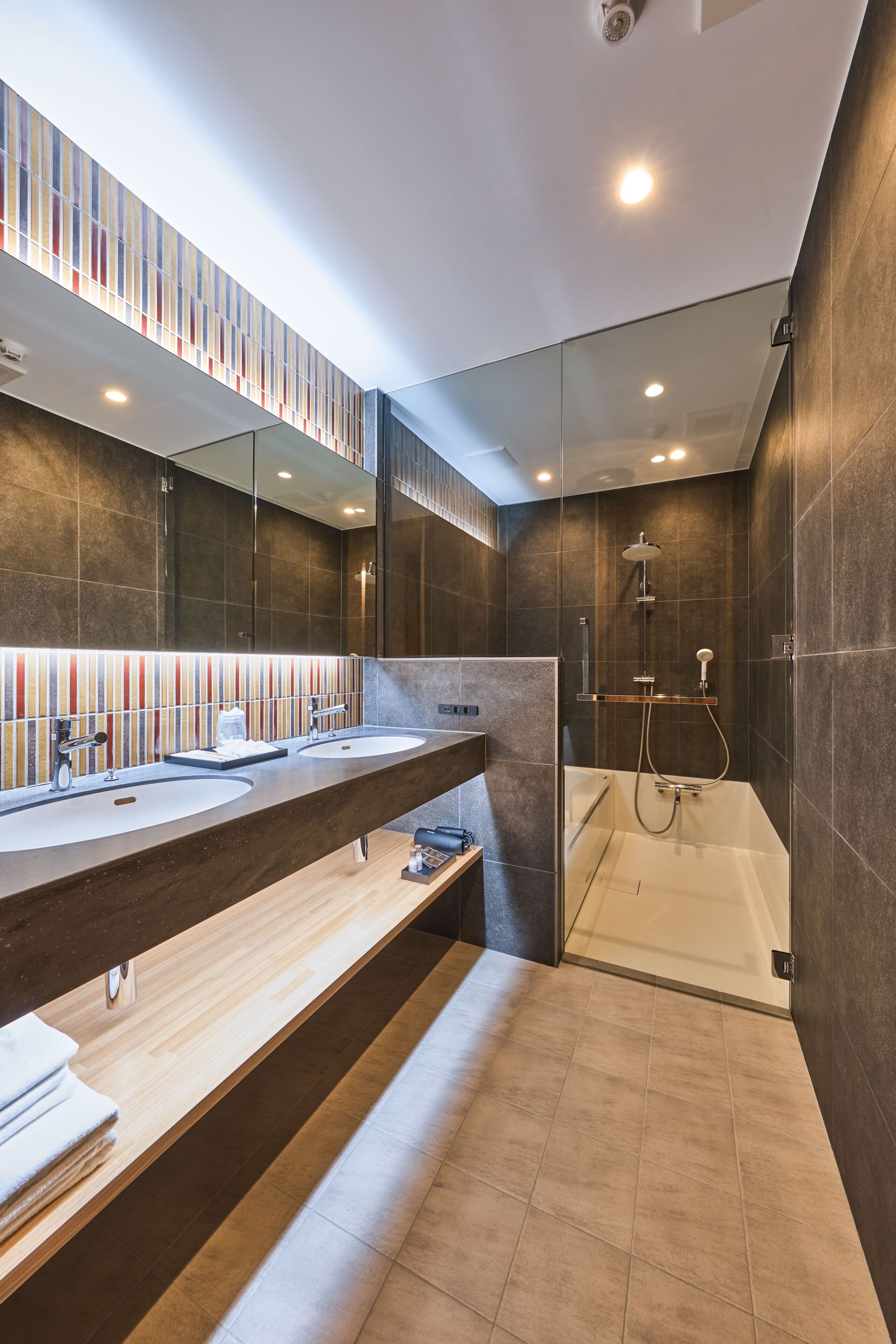 A modern bathroom with dual sinks, a shower, and a glass-enclosed jacuzzi.
