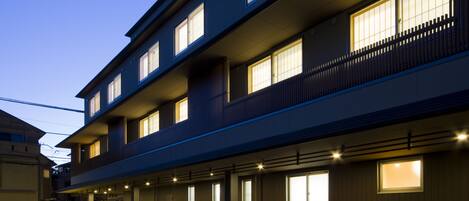 A multi-story hotel with a row of rooms on the ground floor, each with a balcony.