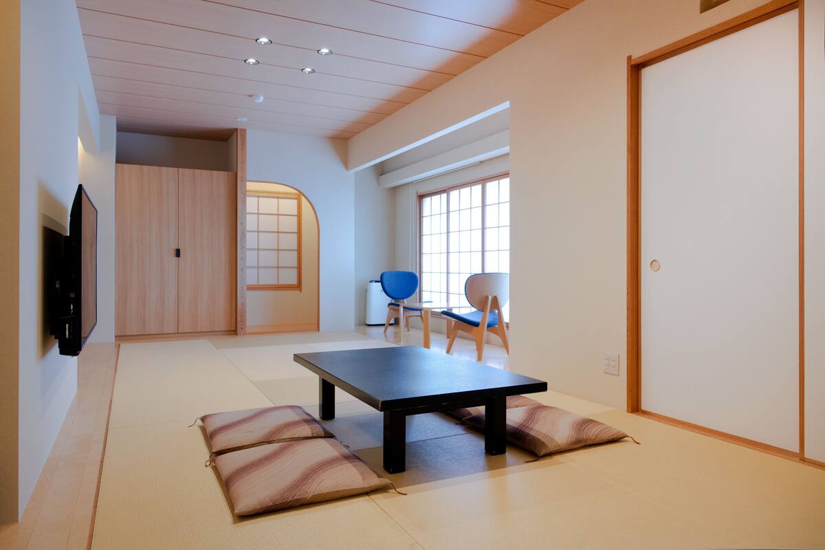 Una habitación amplia con suelo de tatami, una mesa baja y dos sillas.