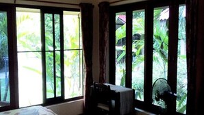 A room with a bed, a desk, and a window with a view of greenery. - Happy Garden villa (Krabi)