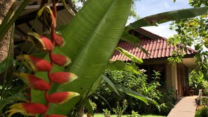 A garden pathway leading to a building with a red-tiled roof, surrounded by lush greenery and potted plants. - Happy Garden villa (Krabi)