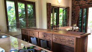 A kitchen with a gas stove, wooden cabinets, and a dining area with a table and chairs. - Happy Garden villa (Krabi)