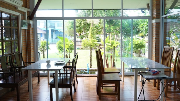 A dining area with a large glass window, wooden chairs, and a table. - Levante (Surat Thani)