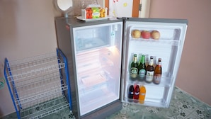 A refrigerator with a blue wire shelf, a wine glass, and a box of fruit on top. - Levante (Surat Thani)