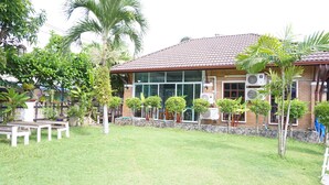 A house with a tiled roof, surrounded by a well-maintained lawn and various plants. - Levante (Surat Thani)